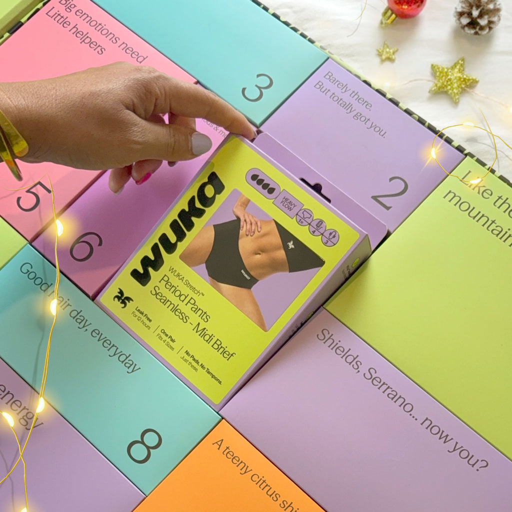 Hand opening the WUKA Period Positive Advent Calendar revealing sustainable seamless midi brief period pants gift