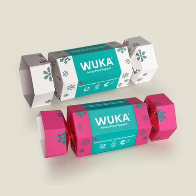 Two WUKA Cracker Gift Boxes – one in pink and the other in white. These festive eco crackers are made from FSC-certified cardboard and filled with sustainable period-proof apparel.