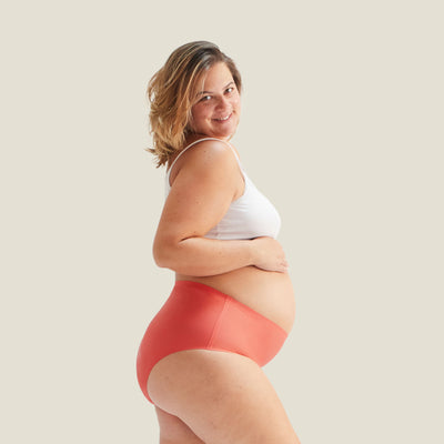 Confident woman wearing WUKA Drytech™ High Waist Incontinence Brief in Coral Pink, designed for light leaks with secure and comfortable coverage.