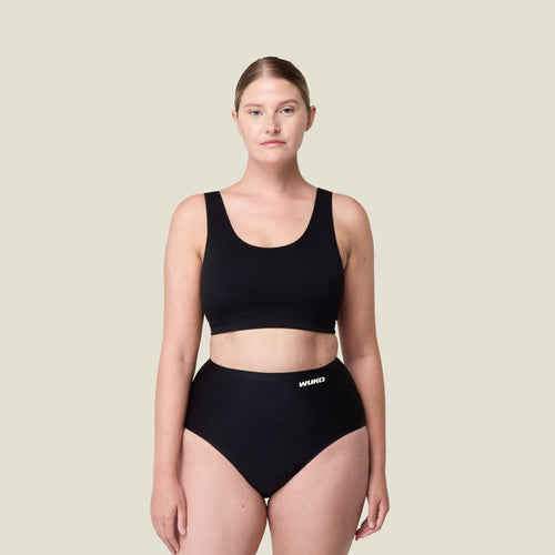 Front-facing view of model wearing WUKA Stretch Seamless High Waist Period Pants for heavy flow, showcasing full body fit and high waist design in black.