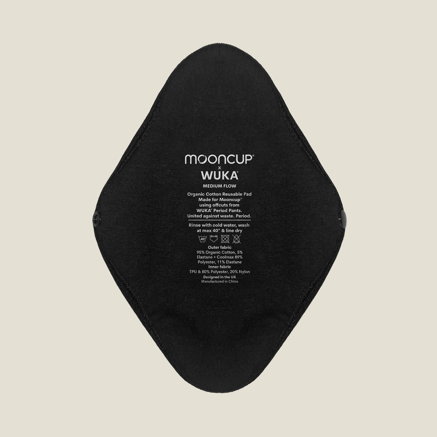 Close-up of WUKA x Mooncup reusable period pad showing organic cotton outer side with printed care instructions for medium flow.