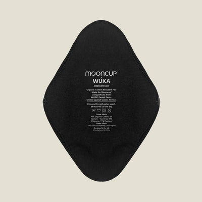Close-up of WUKA x Mooncup reusable period pad showing organic cotton outer side with printed care instructions for medium flow.