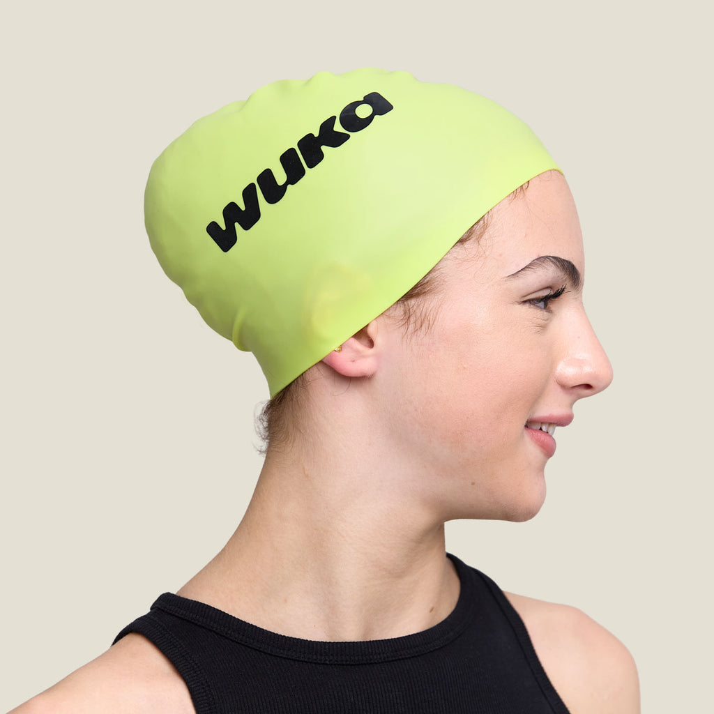 Side profile of teen in WUKA lime green swim cap featuring bold black WUKA logo.