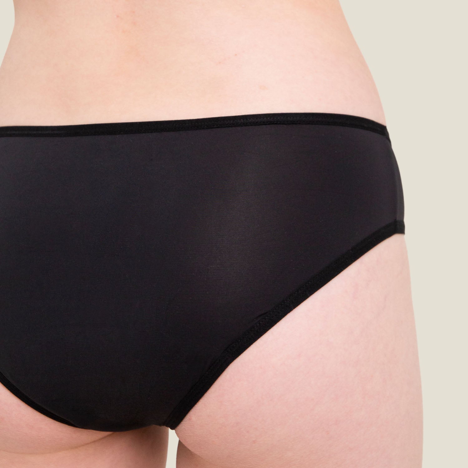 Close-up of fabric and stitching on WUKA Teen Swim Bikini Brief in black, emphasizing soft, stretchy, and water-repellent materials.