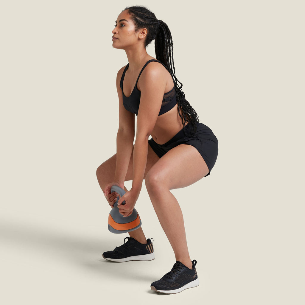 Model performing squat with kettlebell while wearing WUKA Period Sports Shorts, showcasing secure fit, movement support, and protection during workouts.